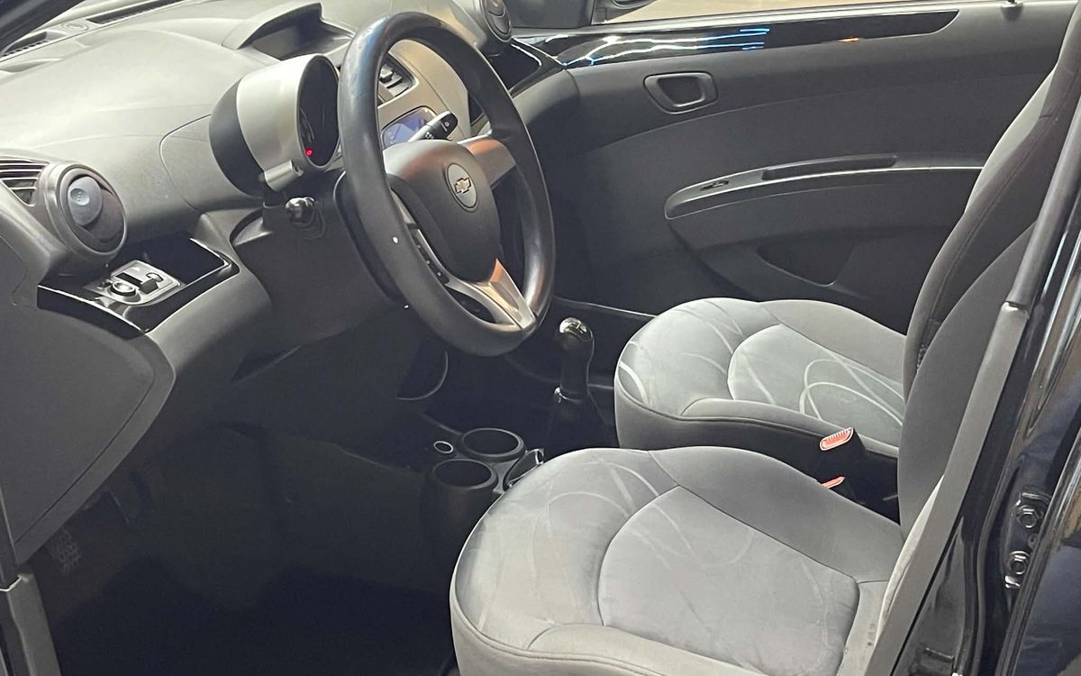 Førerpladsen i den sorte Chevrolet Spark med stofsæder og manuelt gear