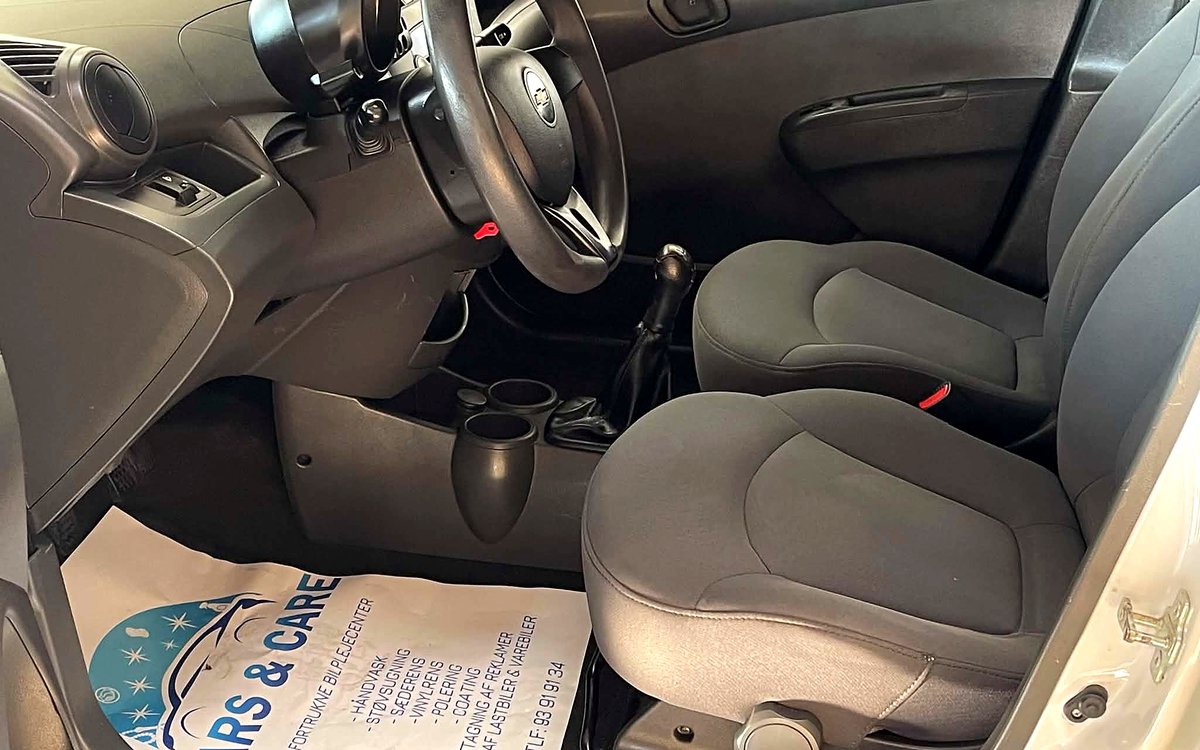 Førerpladsen i den hvide Chevrolet Spark med stofsæder