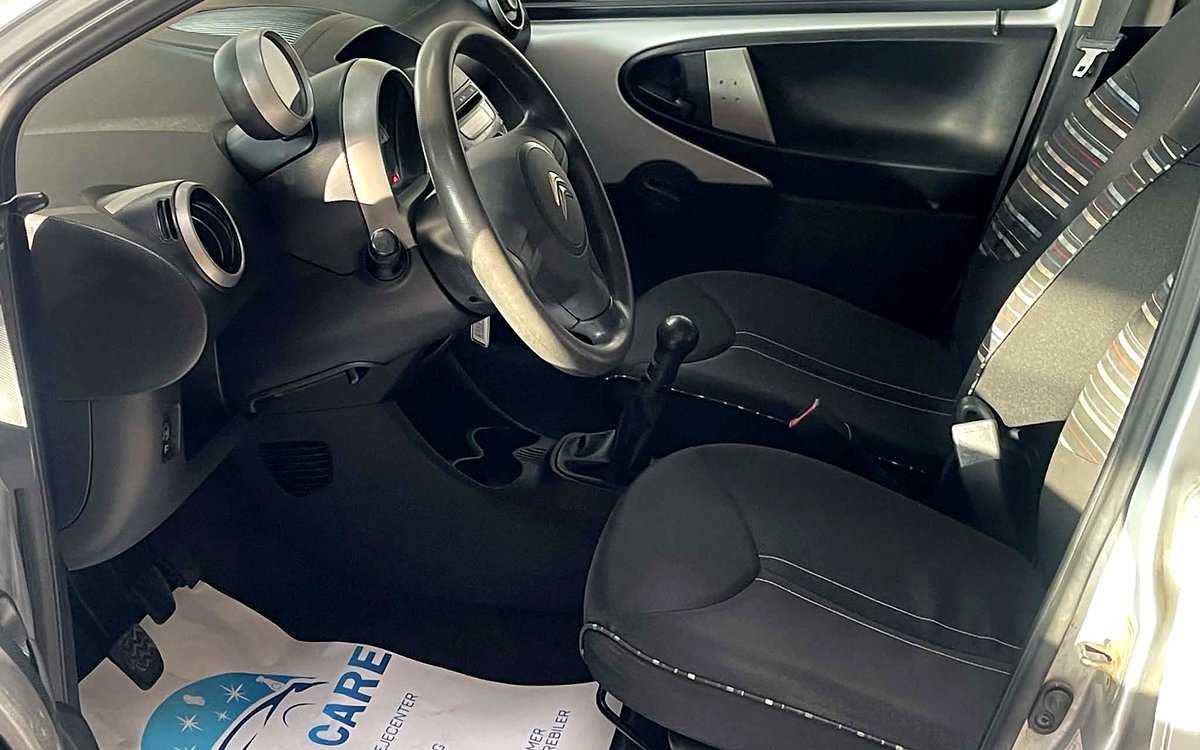 Førerpladsen i den sølvfarvede Citroën C1 med manuelt gear og stofsæder