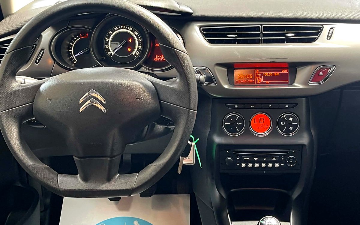 Instrumentbrættet i den mørkeblå Citroën C3 med rat, klimaanlæg, radio og manuelt gear