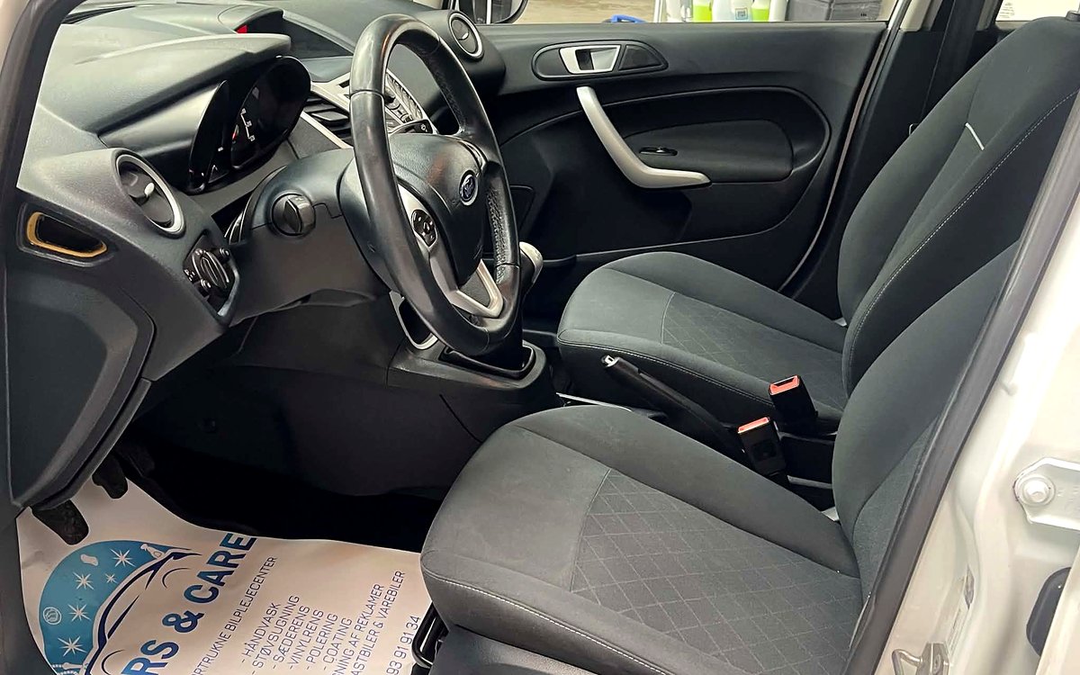 Førerpladsen i den hvide Ford Fiesta med stofsæder