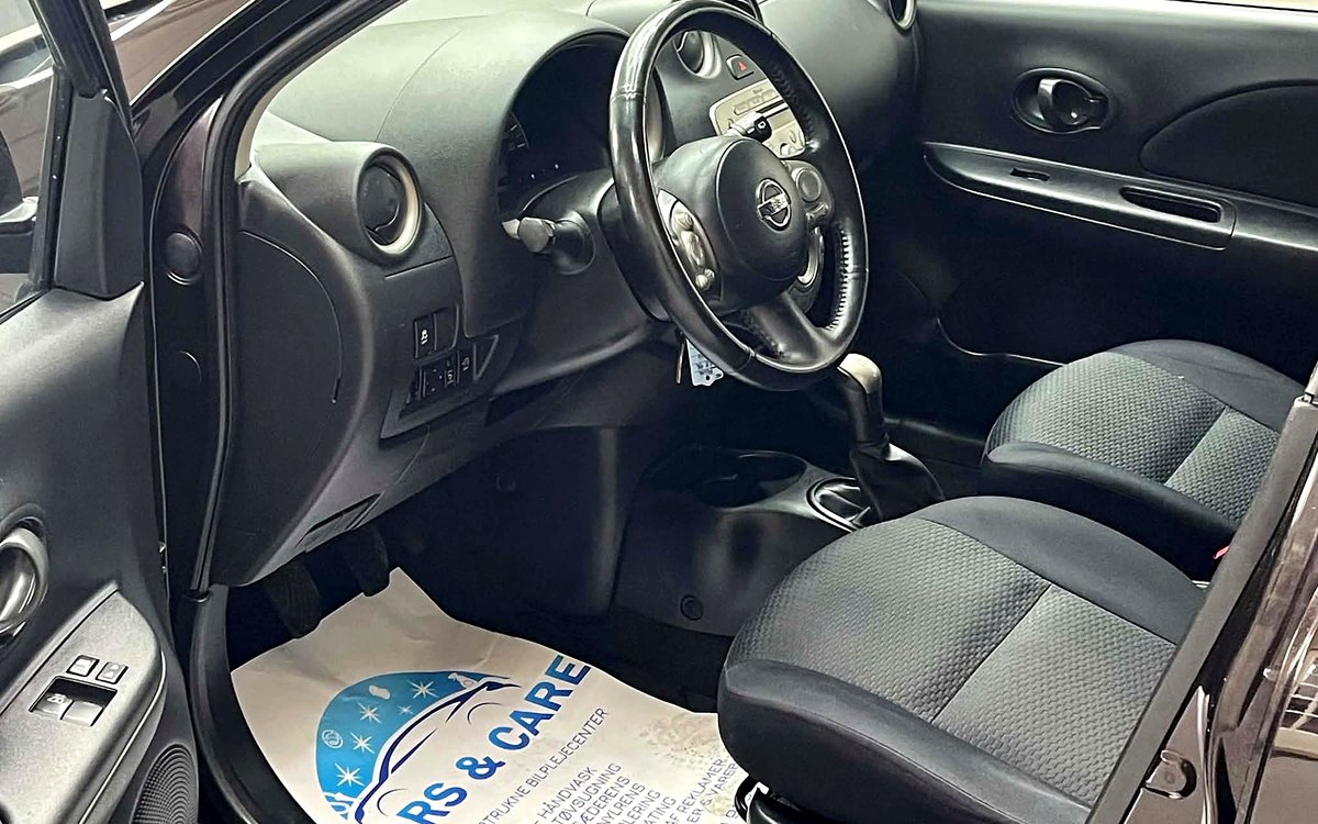 Førerpladsen i den sorte Nissan Micra med rat og stofsæder