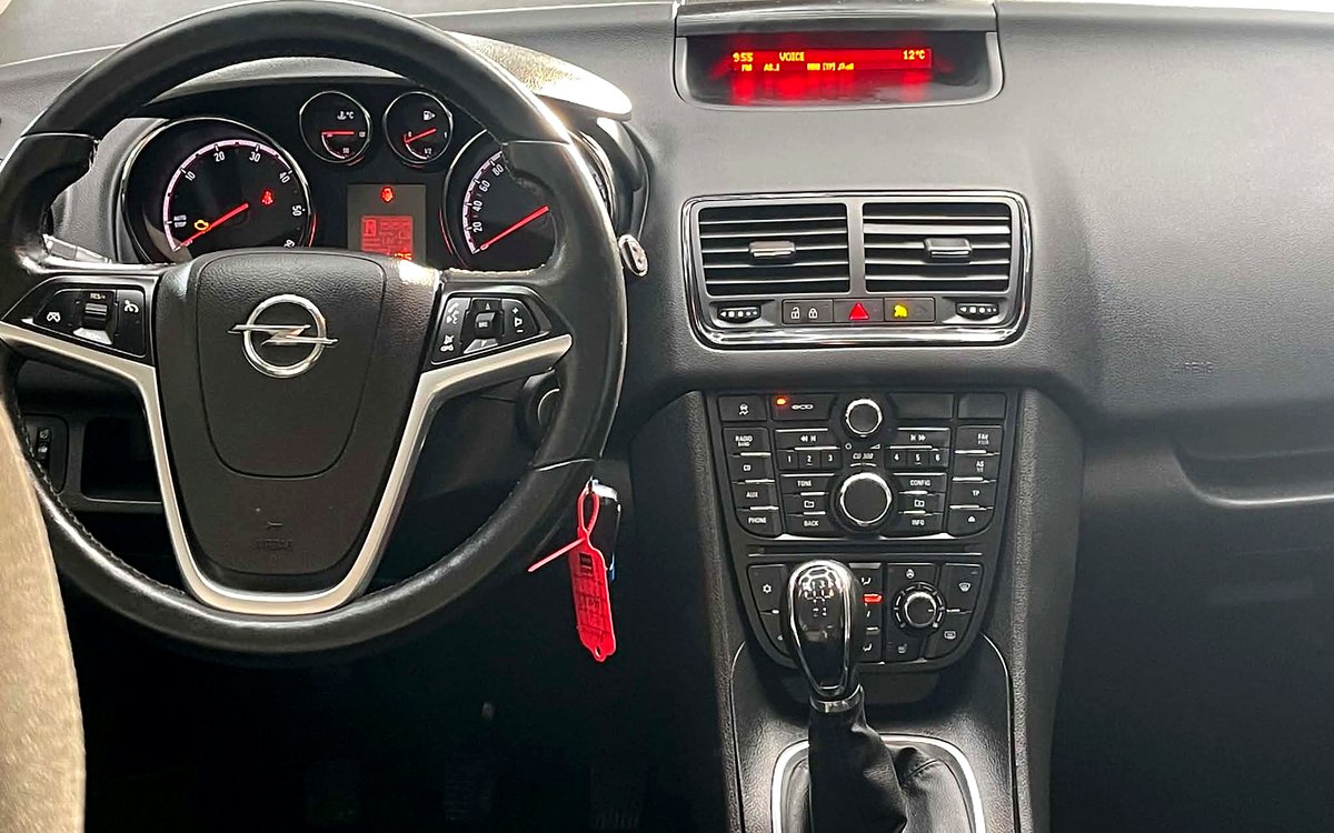 Instrumentbrættet i den sorte Opel Meriva med rat, radio og manuelt gear