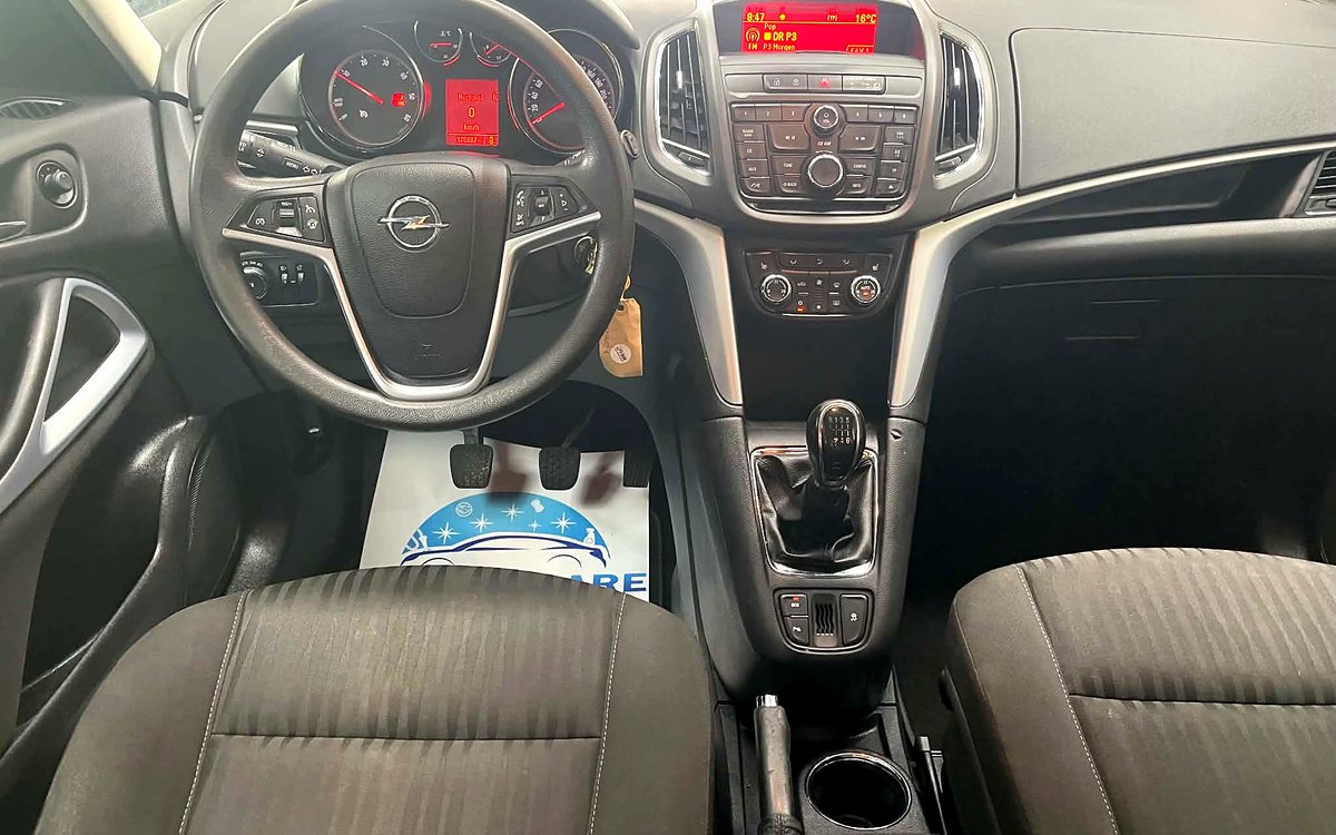Instrumentbrættet i den hvide Opel Zafira med rat, radio og manuelt gear