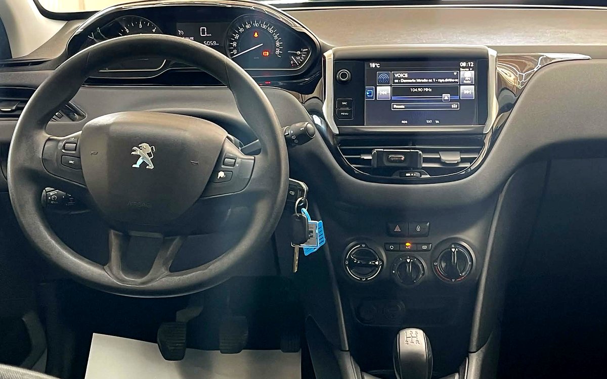 Instrumentbrættet i den mørkegrå Peugeot 208 med skærm, aircondition og manuelt gear