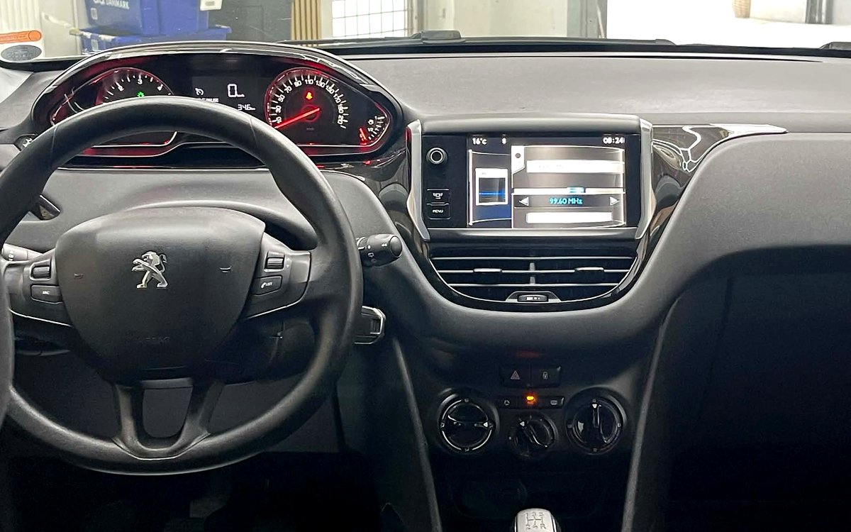 Instrumentbrættet i den hvide Peugeot 208 med skærm, aircondition og manuelt gear