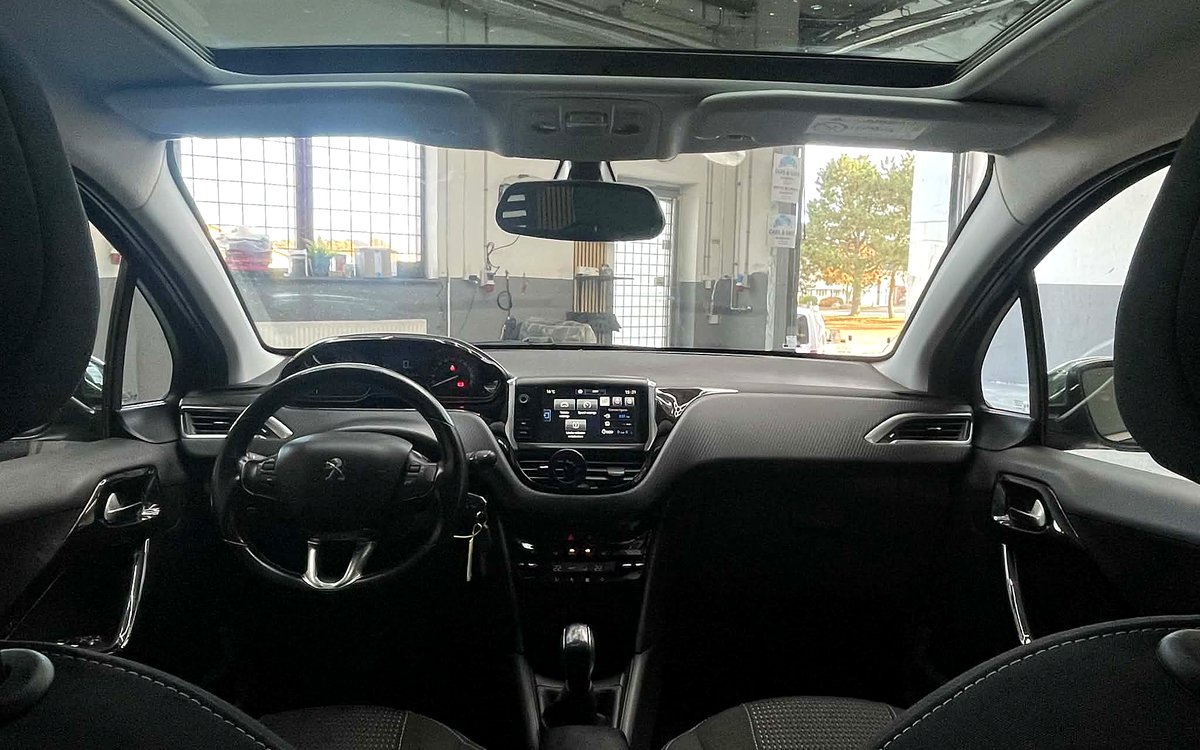 Kabinen i den grå Peugeot 208 med rat, skærm, manuelt gear og glastag