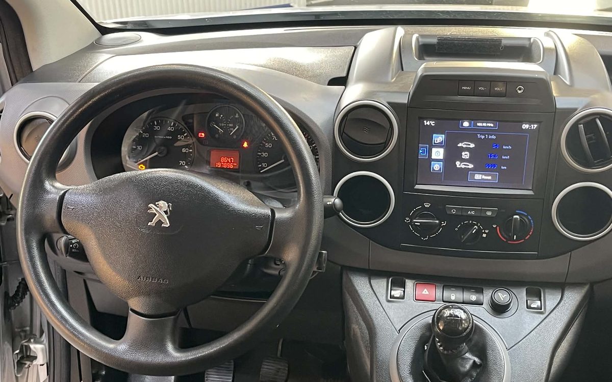 Instrumentbrættet i den sølvgrå Peugeot Partner med rat, touchskærm og manuelt gear