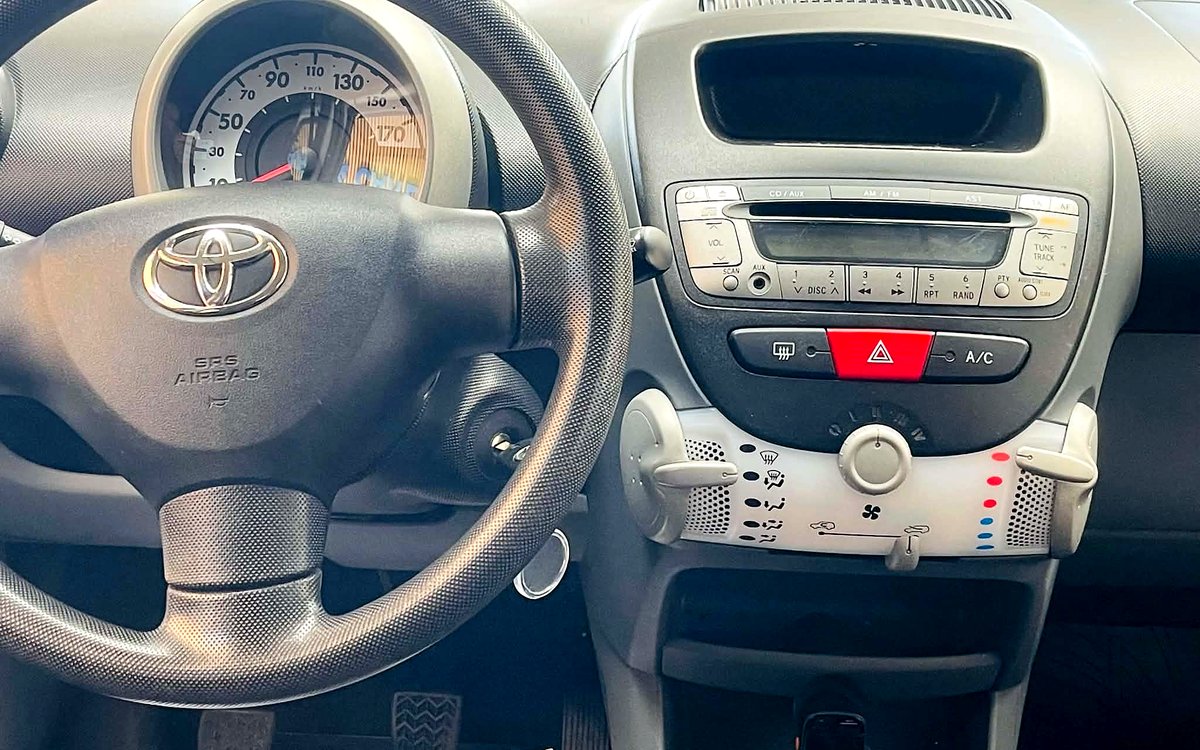 Instrumentbrættet i den hvide Toyota Aygo med radio, aircondition og manuelt gear