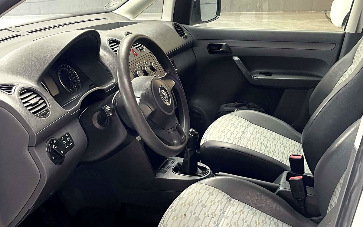Førerpladsen i den hvide VW Caddy Maxi med rat og manuelt gear