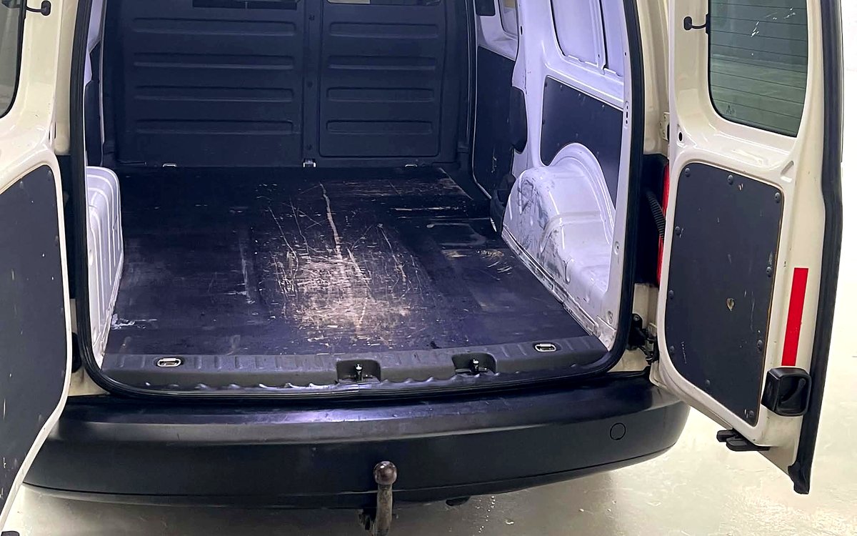 Varerummet i den hvide VW Caddy Maxi set bagfra med dørene åbne og anhængertræk