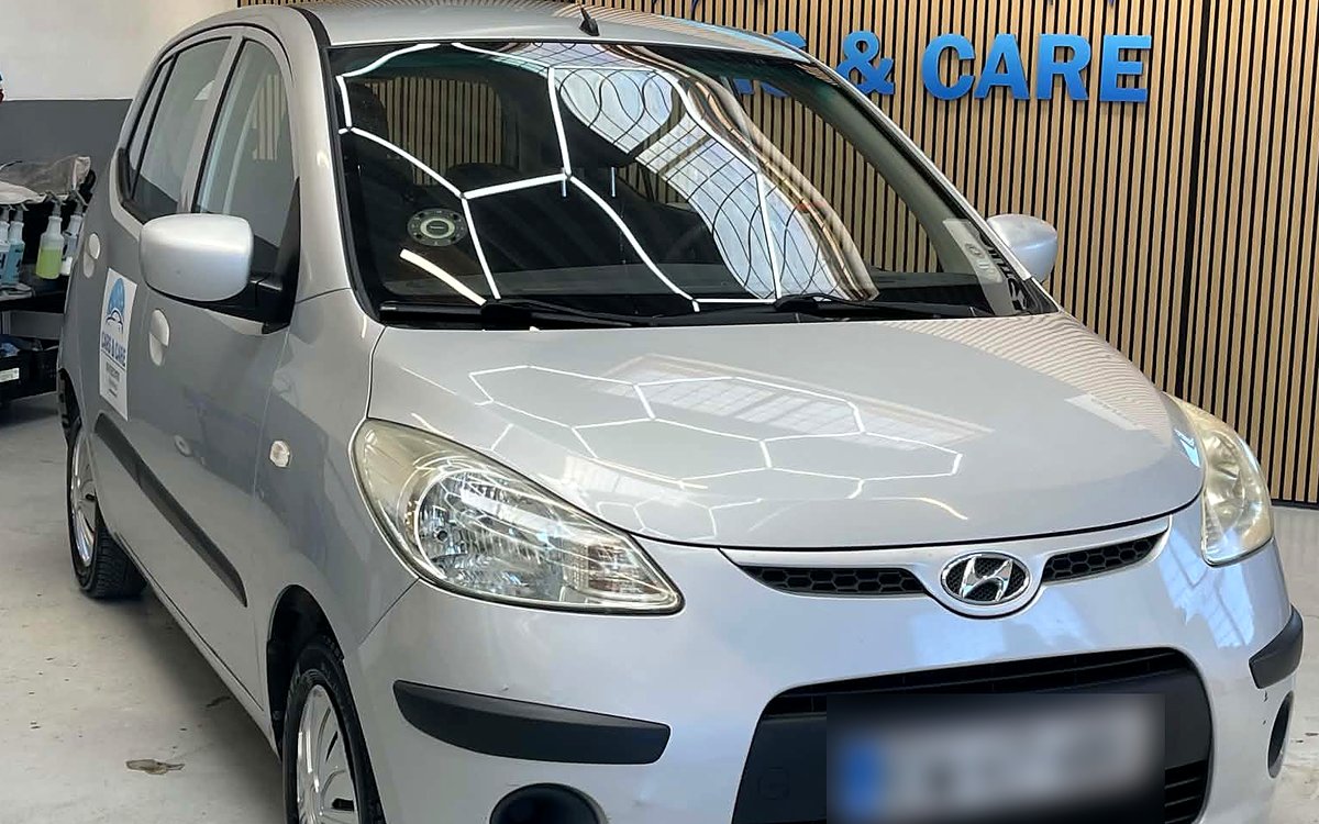 Sølvfarvet Hyundai i10 set skråt forfra, hos Cars & Care i Slagelse