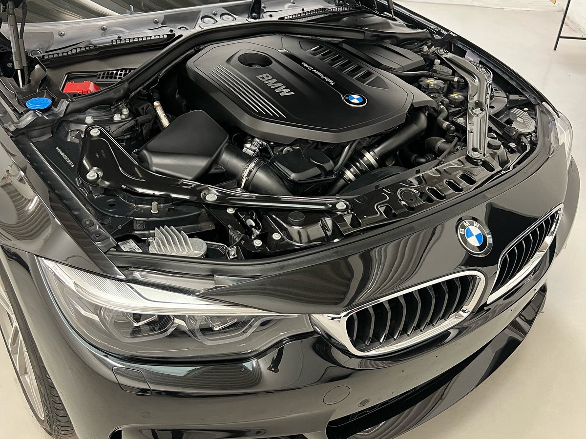 Sort BMW med åben motorhjelm og rent motorrum på værkstedet
