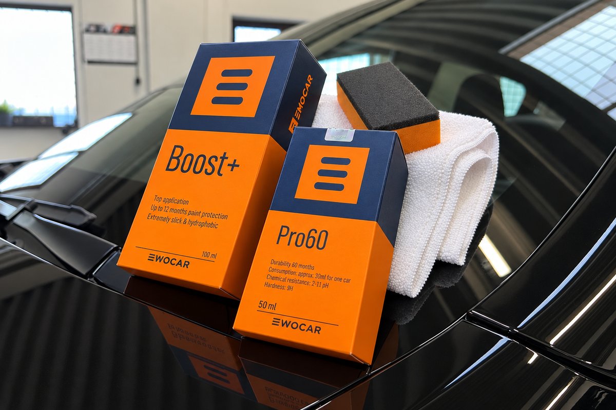 Æsker med coating, en påføringssvamp og en mikrofiberklud på den blanke, sorte motorhjelm på en bil i værkstedet