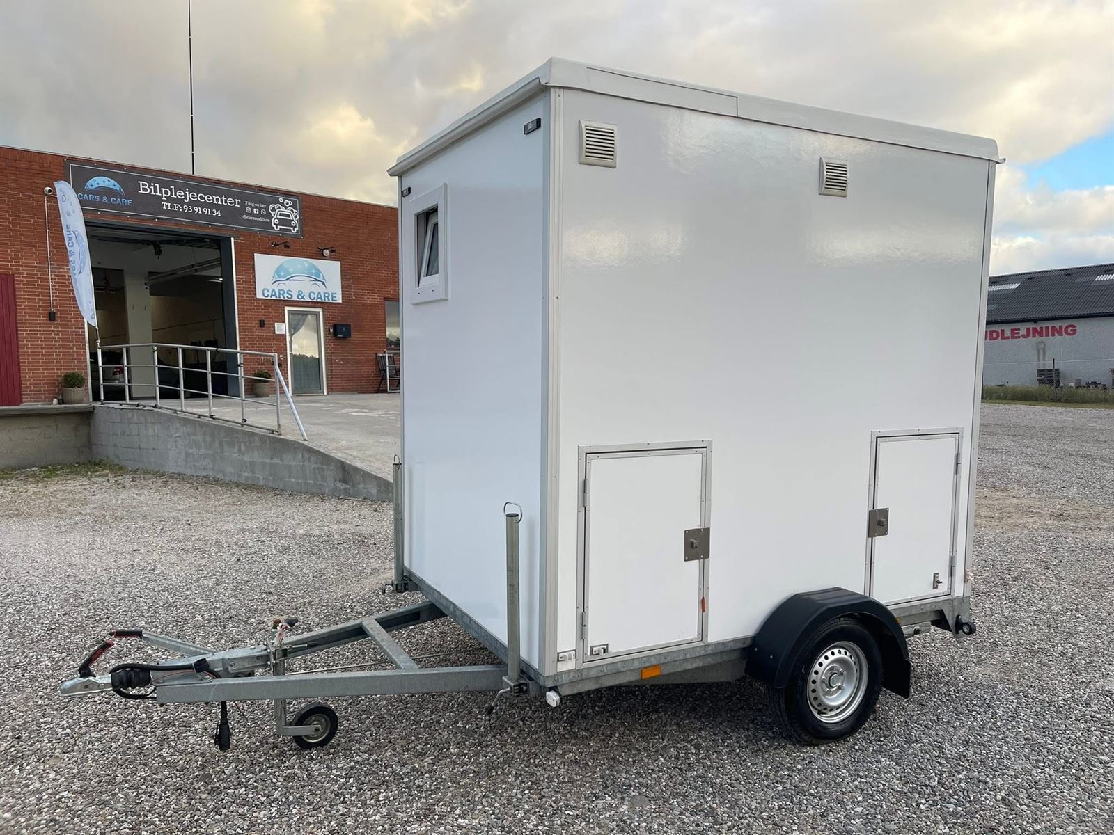 Samme trailer ren og hvid uden graffiti foran værkstedet