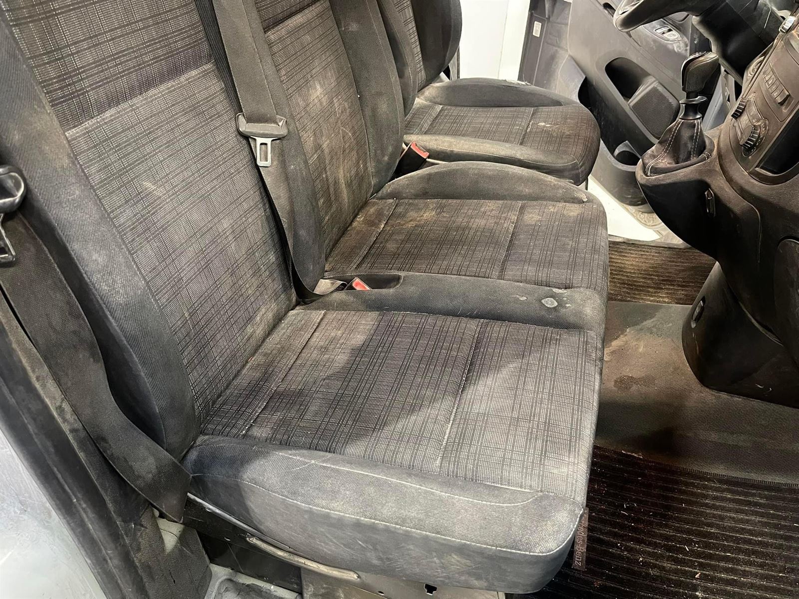 Forsæder i stof med pletter og snavs og et snavset gulv før rens
