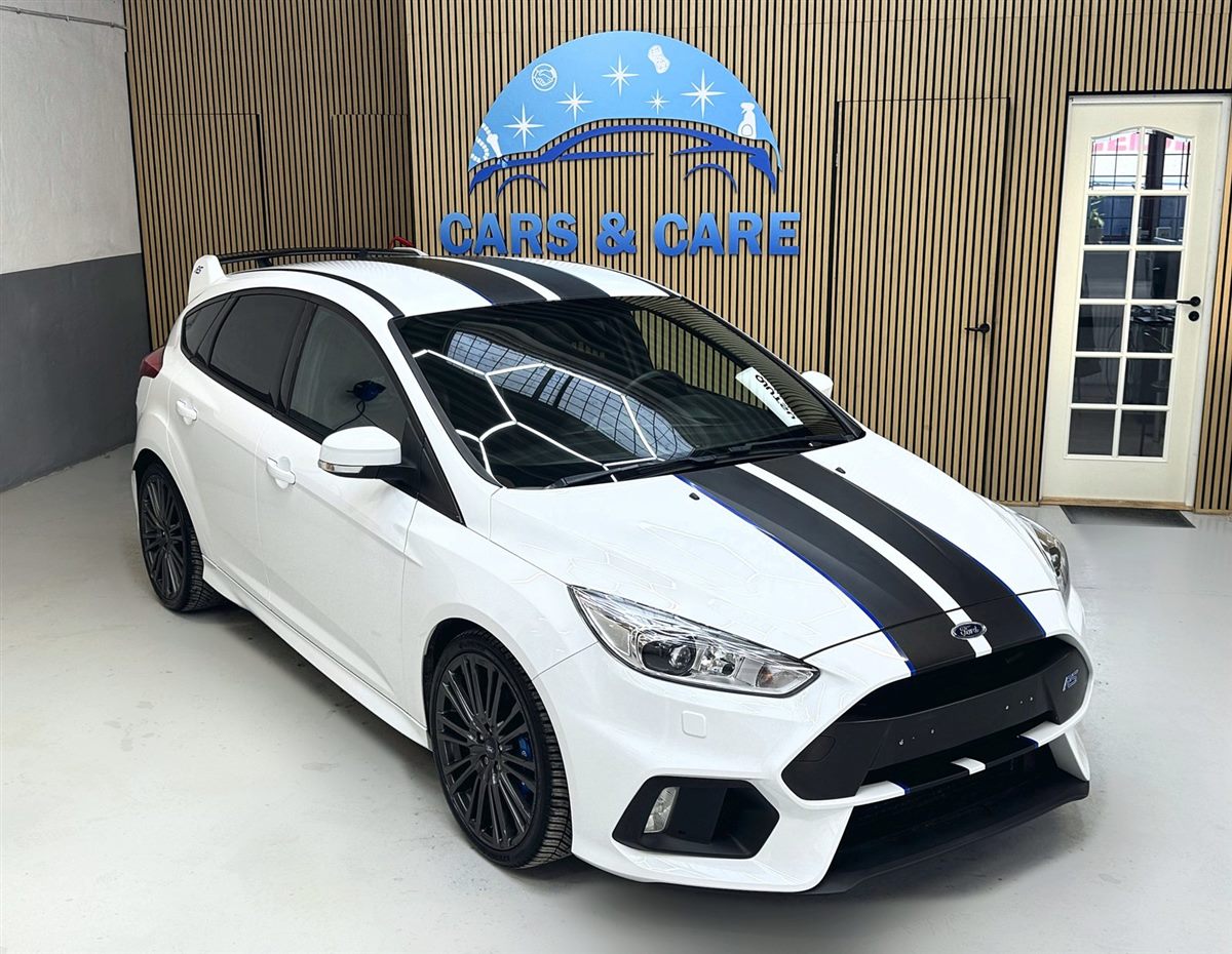 Hvid Ford Focus RS med sorte striber, ren og blank i værkstedet foran Cars & Care-skiltet på trævæggen