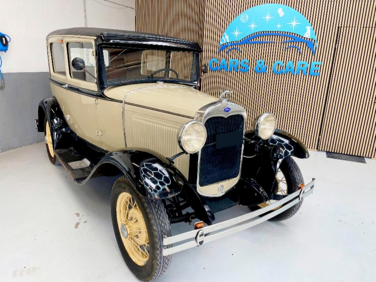 Beige og sort veteranbil fra Ford i værkstedet foran væggen med Cars & Care-logoet