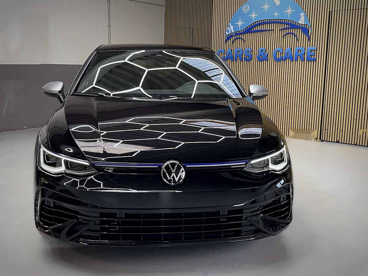 Blank, sort VW Golf R set forfra på det lyse værkstedsgulv foran Cars & Care-logoet